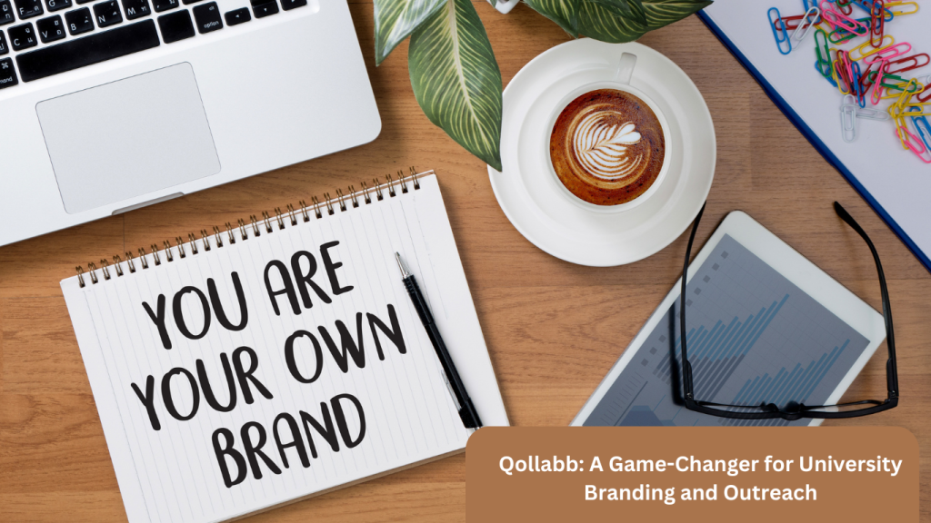 Notebook with 'You Are Your Own Brand' written on it, placed on a wooden desk alongside a laptop, tablet, coffee cup, and office supplies."